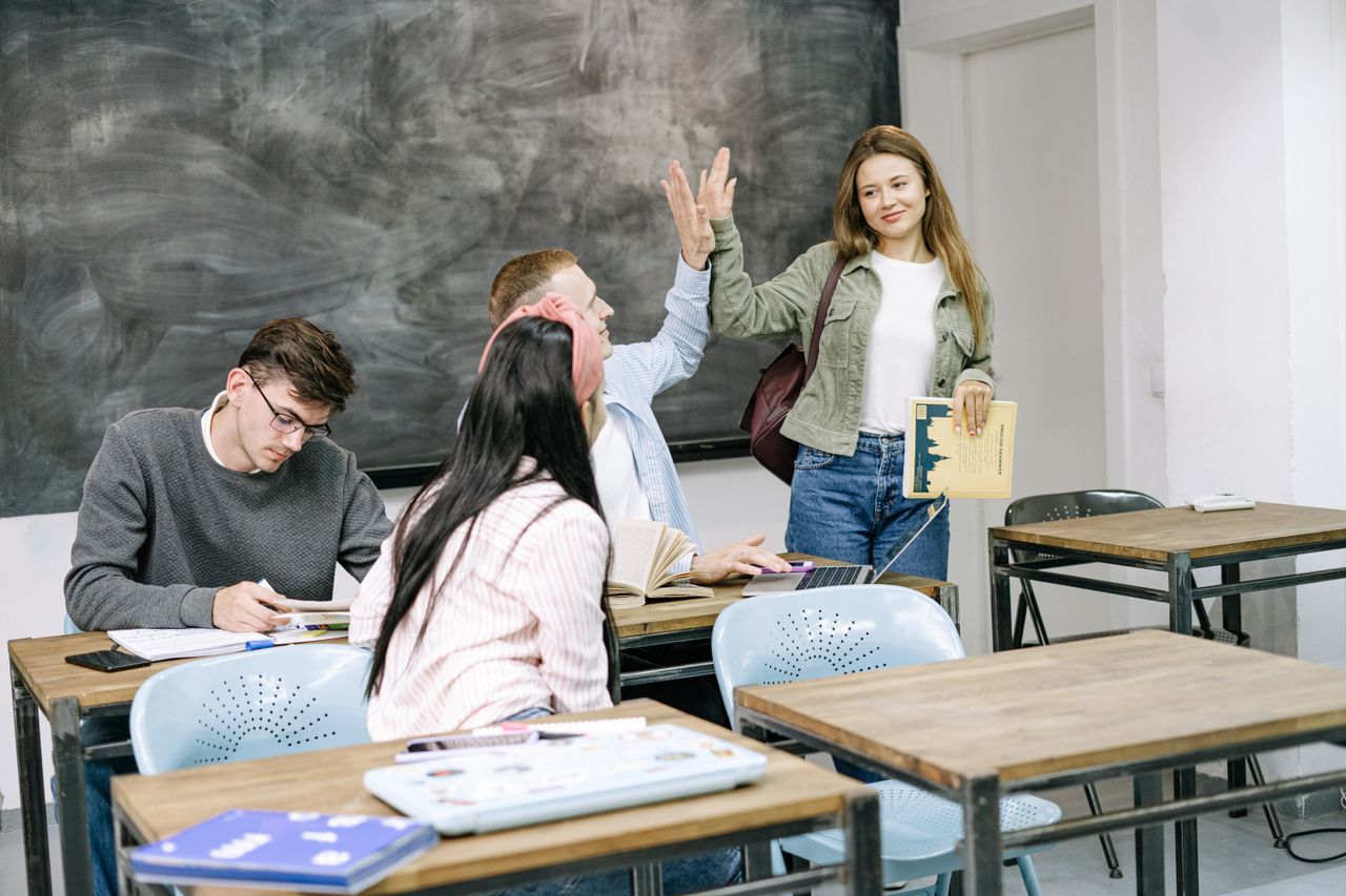 Group of students interacting and studying in a college classroom setting.