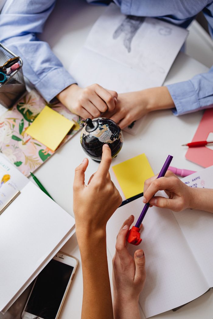 Students collaborate on a creative school project with a globe and notes.