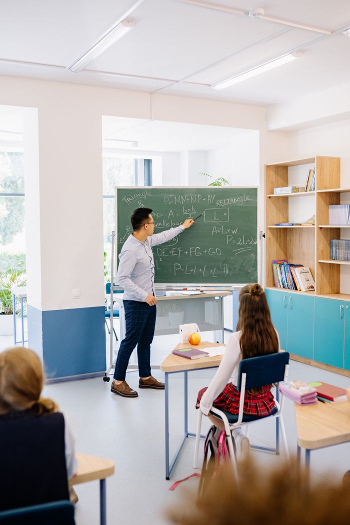 Instructor teaching students in a bright classroom, emphasizing interactive learning.